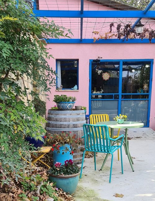 פינת ישיבה צבעונית בחצר יקב לצד חבית עץ וצמחייה