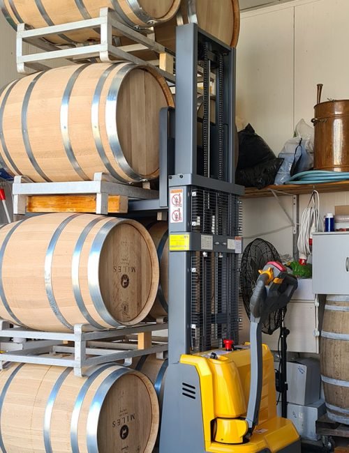 חביות יין על מתקן אחסון לצד מלגזה